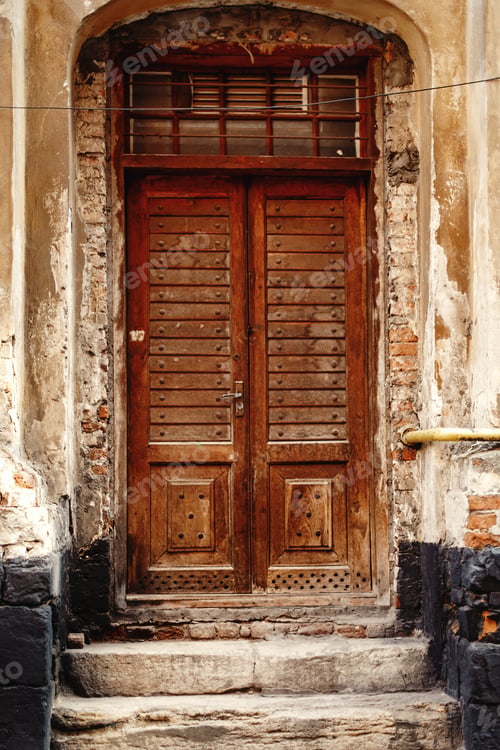 Preview: Old wooden door front on stone wall in the european city
