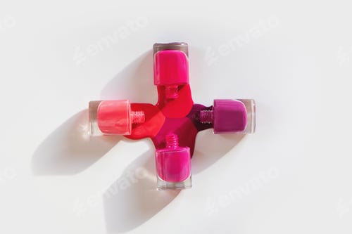 Preview: Top view of various nail polishes spilled on white background.