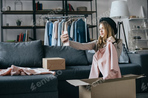 Preview: fashion blogger holding dress and taking selfie with smartphone