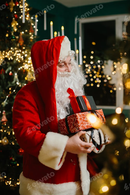 Preview: Santa claus holding christmas gifts near christmas tree