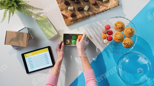Preview: Top view of unrecognizable woman packing biscuits, processing orders desktop concept.