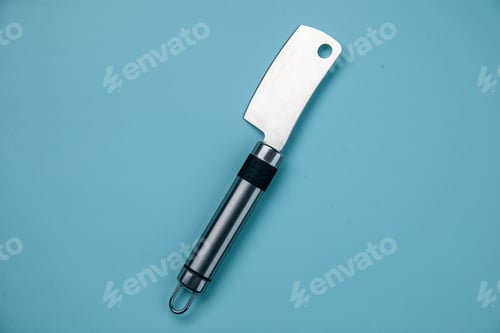 Preview: Horizontal view of stainless meat cleaver lying on pastel blue wave background with free space