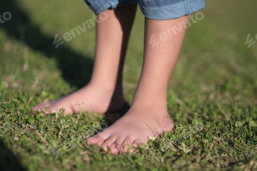 Preview: Barefoot little boy enjoying the soft grass beneath his feet on a sunny day.