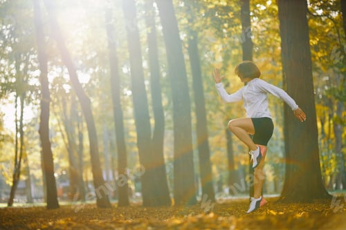 Preview: Side view of woman jumping at park during morning workout
