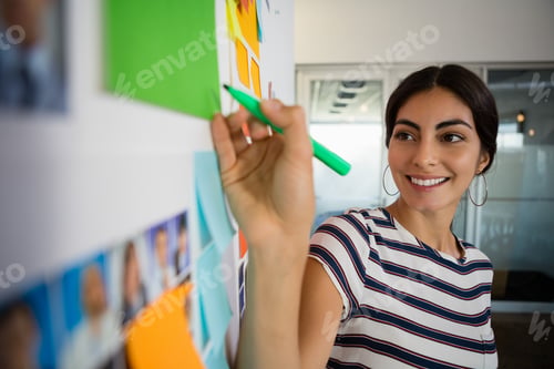 Preview: Smiling woman writing on sticky note in office
