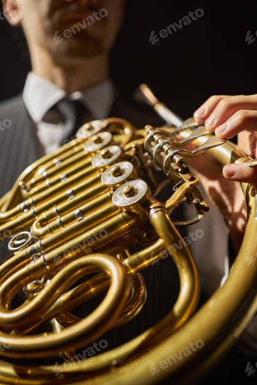 Preview: Musician Pushing Valve Levers of Golden French Horn Playing Music under Bright Light