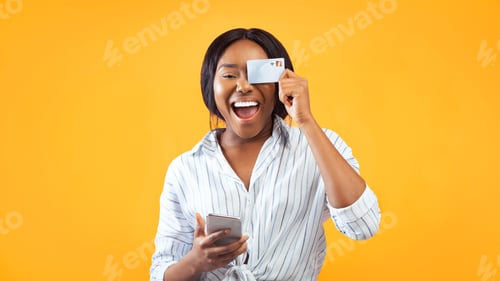 Preview: Woman Holding Smartphone And Credit Card Having Fun In Studio