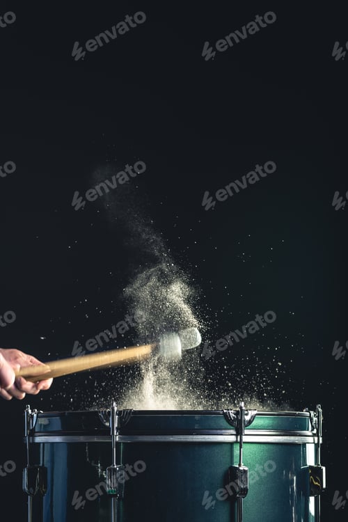 Preview: A man plays a musical percussion instrument with sticks on a dark background.