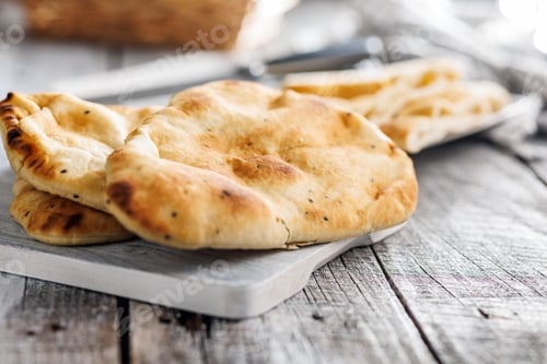 Preview: Freshly Baked Naan Bread on cutting board on wooden table