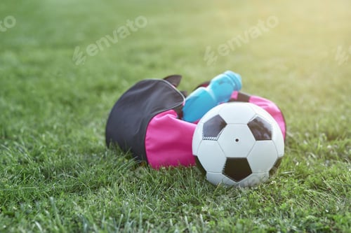 Preview: Soccer ball, bottle of water and sports bag on green grass