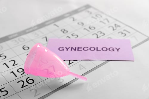Preview: Menstrual cup, calendar and card with word GYNECOLOGY on light background