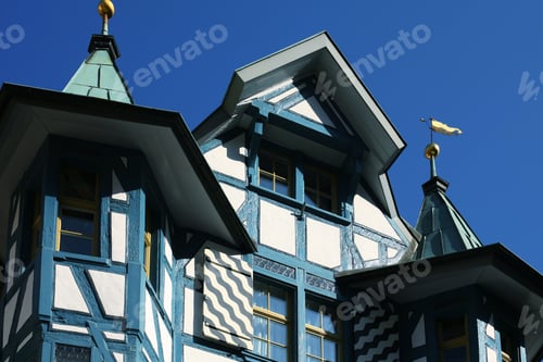 Preview: Close-up of a traditional European half-timbered building facade against a clear blue sky.