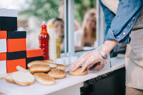 Preview: cropped shot of male chef cutting buns white cooking at food truck