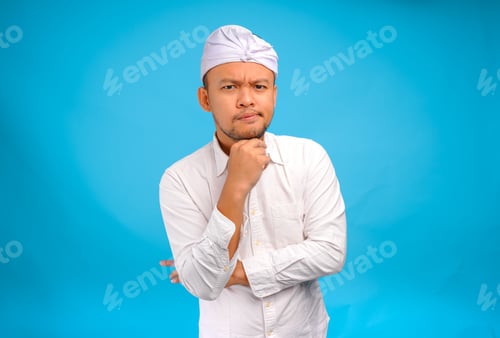 Preview: Confused Balinese man in traditional udeng thinking hard with serious expression.