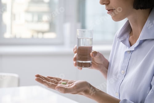 Preview: Tired businesswoman with headache going to have glass of water and painkiller