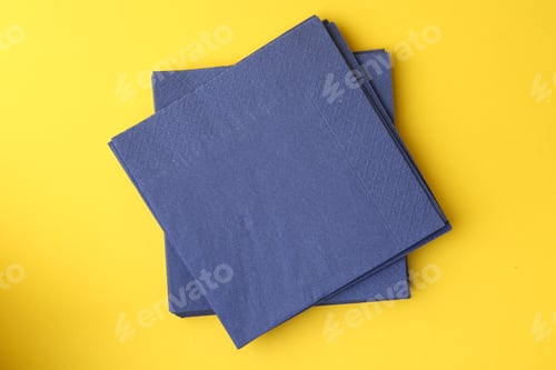 Preview: Stack of blue handkerchiefs on yellow background, top view