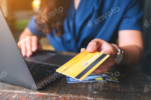 Preview: People holding and giving a credit card to someone while using laptop computer