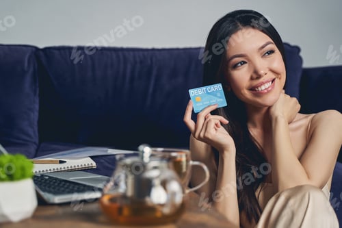 Preview: Beautiful lady holding debit card and smiling