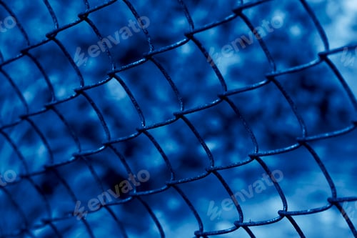 Preview: Wire fence or metal net on blurred background toned in color of the year 2020 classic blue.