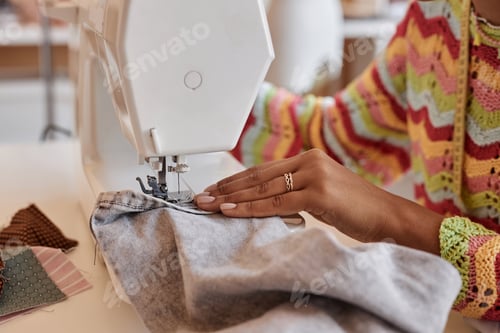 Preview: Hand of young African American woman sewing denim clothes
