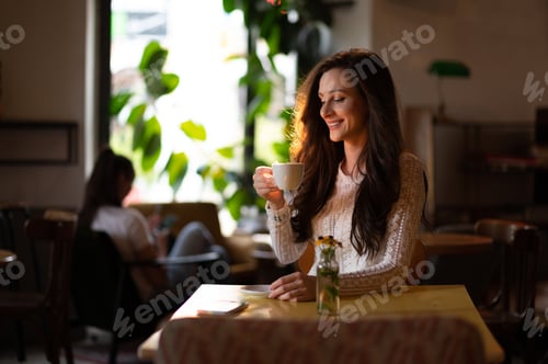 Preview: Portrait of beautiful young woman drinking coffee or tea in a cafe