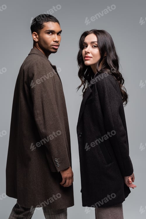 Preview: young african american man in coat near stylish woman in black blazer isolated on grey