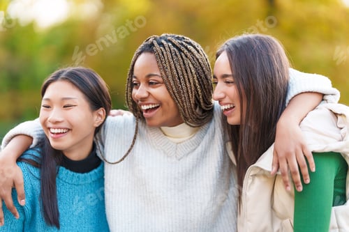 Preview: Multiethnic friends embracing while smiling in the park