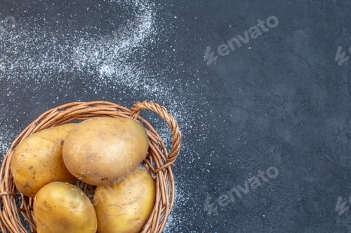 Preview: Top view of raw potatoes in a wooden basket on black white background with free space