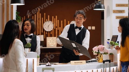 Preview: Male receptionist searching guest reservation in the registry