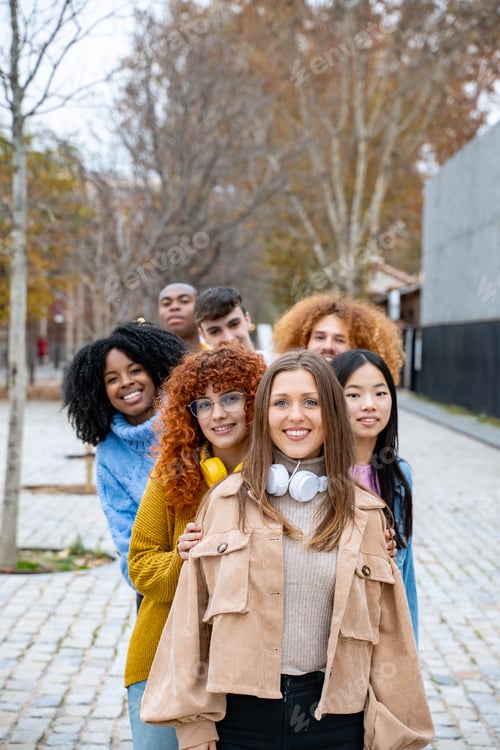 Preview: Young multiethnic friends smiling while posing standing in a row outdoors.