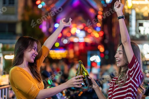 Preview: Asian young woman friends hold bottle of beer, having party in the bar.