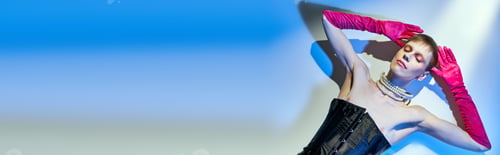 Preview: top view, queer model in corset and pink gloves lying on blue backdrop, closed eyes, banner