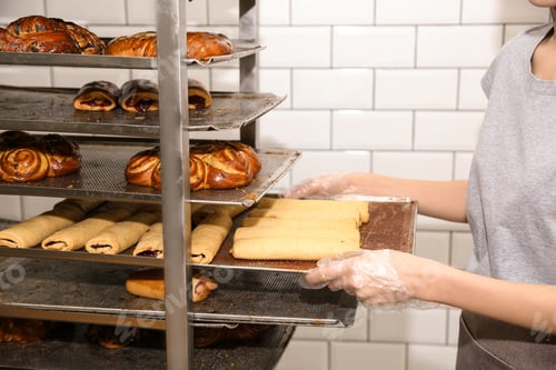 Preview: Baker taking out tray with pastry from rack in workshop, closeup