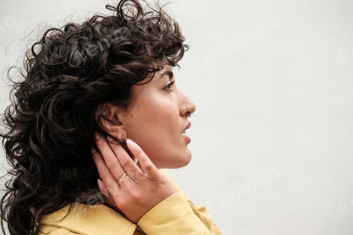 Preview: Young woman touching hair and looking away on white background