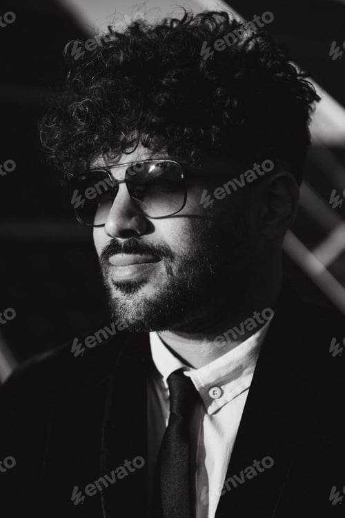 Preview: Arab businessman wearing sunglasses and looking away