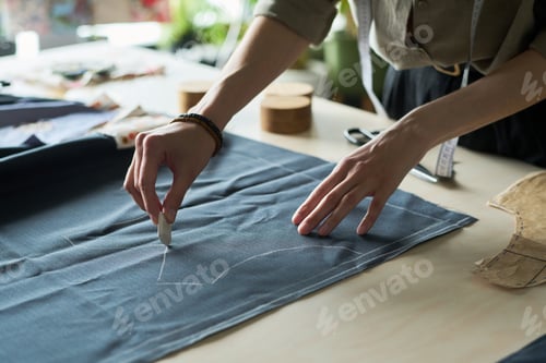 Preview: Young Adult Caucasian Woman Drawing Pattern on Fabric While Designing Garment
