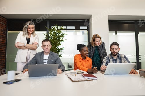 Preview: Group of People Sitting Around a Table With Laptops