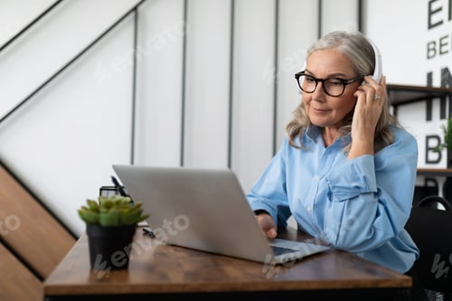 Preview: caucasian businesswoman in headphones watching webinar on laptop in office