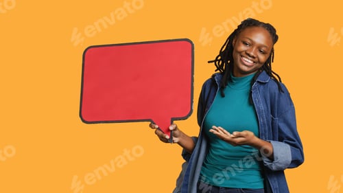 Preview: Smiling woman holding red speech bubble sign, studio background