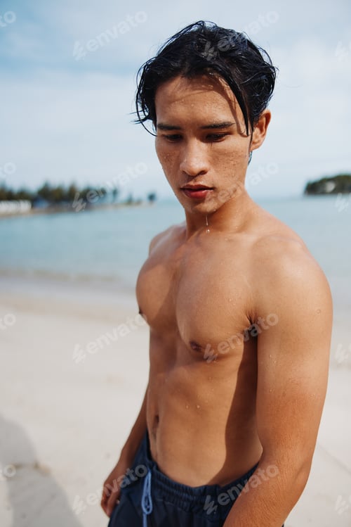 Preview: Muscular Asian Man Smiling on Tropical Beach with Palm Trees and Crystal Clear Ocean Water
