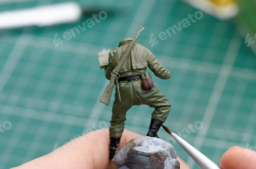 Preview: Painting shoes on a plastic model of a soldier close up.