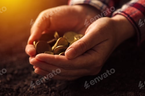 Preview: Farmer with handful of coins over soil land
