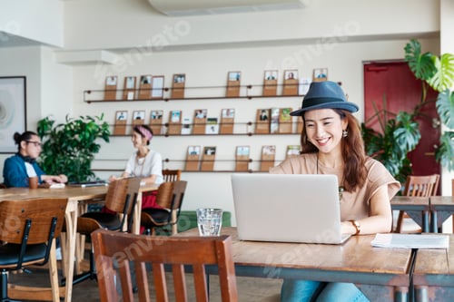 Preview: Group of young Japanese professionals working on laptop computers in a co-working space.