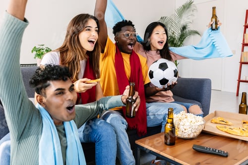 Preview: Diverse young football fans friends watching soccer on television TV at home