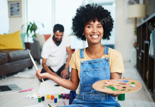 Preview: Shot of a young woman holding a paint palette while her boyfriend sits in the background