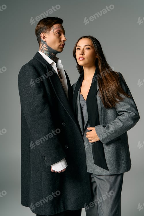Preview: Stylish young couple poses elegantly in fashionable attire against a soft grey background