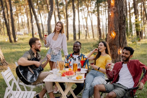Preview: Multiracial group of people, bearded hipster man playing guitar and friends dancing and singing