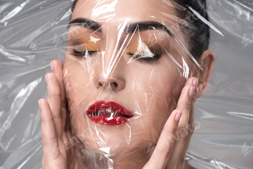 Preview: beautiful young woman with closed eyes holding transparent mask on grey