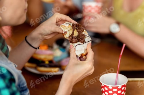 Preview: Close-up of woman eating glazed chocolate donut.