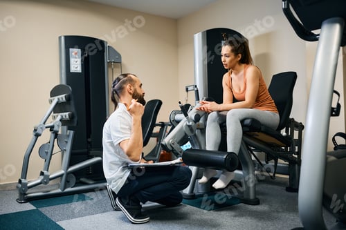Preview: Athletic woman talking with her physiotherapist about future sports plans in health club.